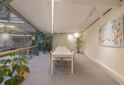 Long white meeting table in a minimalist room with abstract wall art.
