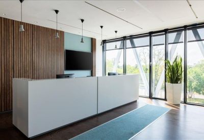 Sleek white reception desk with wood paneling and large windows.