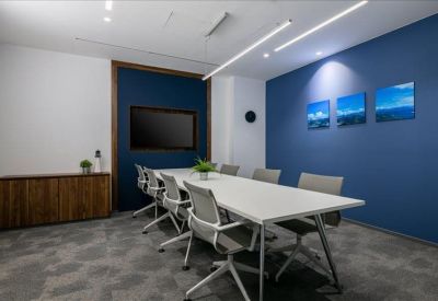 Spacious boardroom featuring a blue accent wall, wall-mounted screen, and white table.