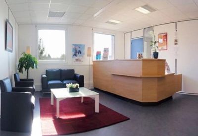 Reception area with a wooden desk, blue seating area, and a red rug.