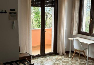 Workspace area with a white desk and chair set against a balcony door with shutters.