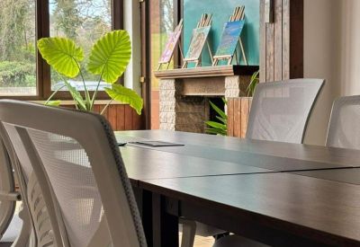 Professional meeting table with mesh office chairs and small paintings on a fireplace mantel.