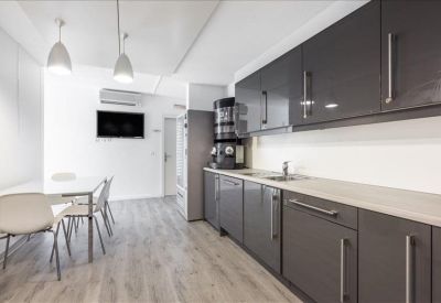 Sleek grey kitchen area with a dining table and pendant lighting.