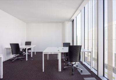 Bright, white corner office with white desks and black ergonomic chairs.
