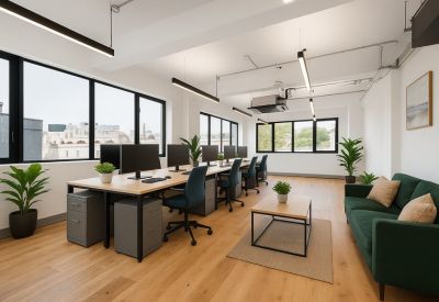 Bright open-plan office with wooden floors, desks, and green sofa.