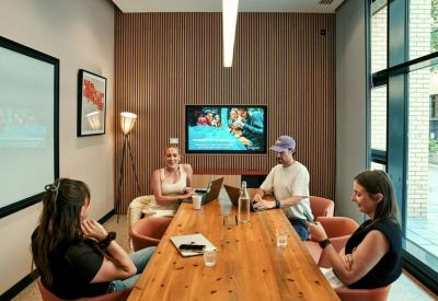 Private meeting room with a wooden table, wall-mounted screen, and warm lighting.