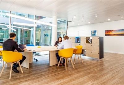Sunlit communal area with a long white table and vibrant yellow chairs.