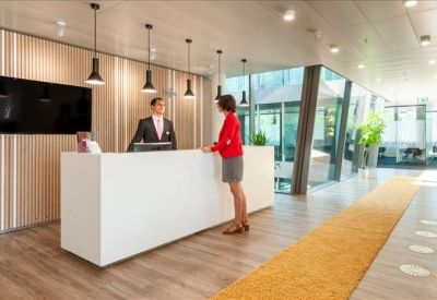 Sleek white reception desk with wood-paneled walls and hanging lamps.