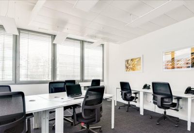 Bright open-plan office with white desks and black ergonomic chairs.