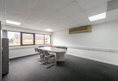 Meeting room with a central oval table, grey chairs, and an air conditioning unit.