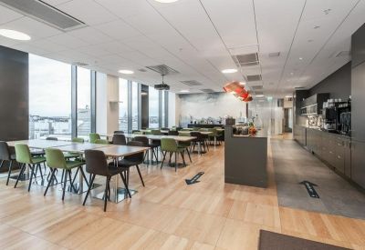 Spacious open-plan coworking area with natural light and long wooden tables.