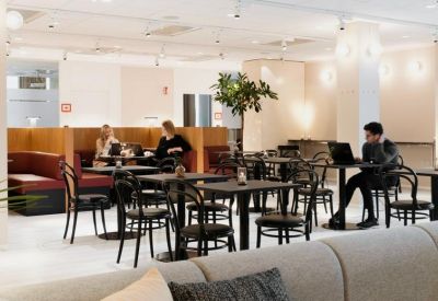 Quiet coworking zone with individual café tables and cushioned bench seating.