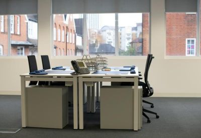 Bright office space with white desks and large windows.