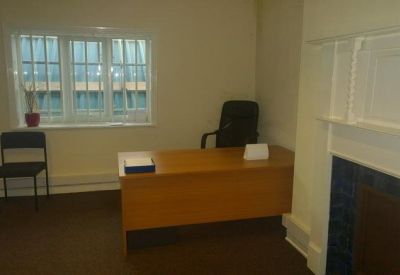 Private office featuring a large wooden desk and task chair by a window.