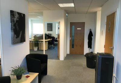 Reception waiting area with a black tub chair and a glass door leading to the office.