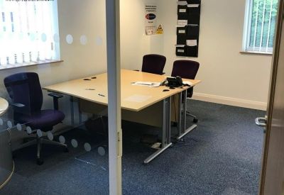 Private meeting room with a light wood table and purple chairs viewed through a glass partition.