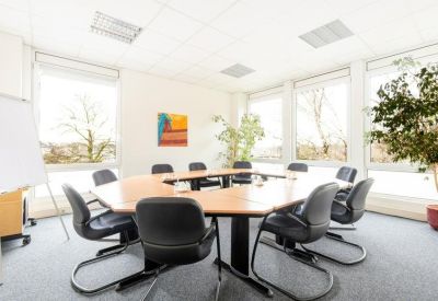 Spacious conference room featuring a U-shaped wooden table and indoor plants.