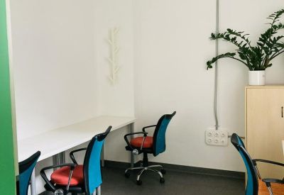 Bright office space with long white desks and colorful blue and orange chairs.