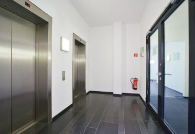 Elevator lobby featuring stainless steel doors and dark tiled flooring.