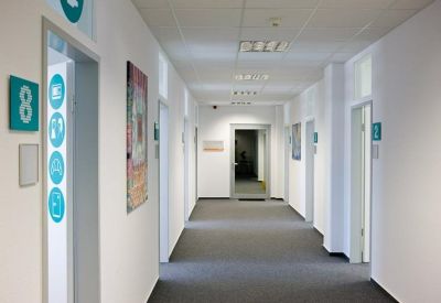 Bright white corridor with grey carpeting and numbered office doors.