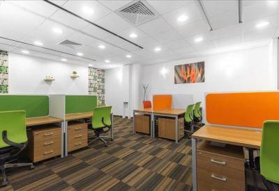 Bright coworking area with green and orange privacy screens and wooden desks.