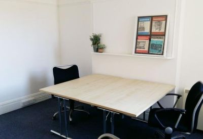Private office space featuring a light wood desk and black ergonomic chairs.
