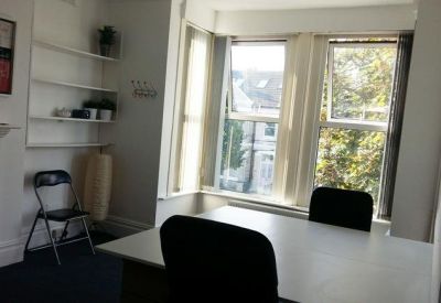 Meeting room with a white table and large bay windows offering natural light.