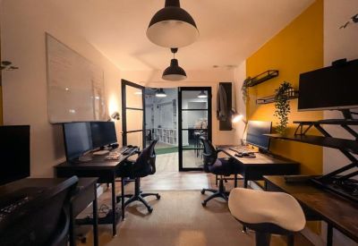 Narrow office space featuring multiple workstations and a vibrant yellow accent wall.
