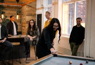 Communal breakout area with a pool table and team members socializing.