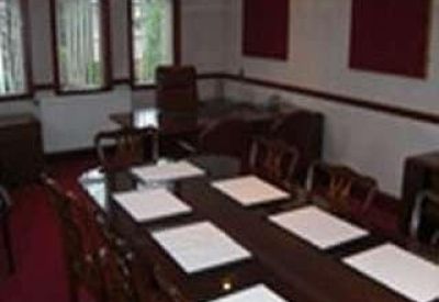 Traditional boardroom with a long wooden table and red carpet.