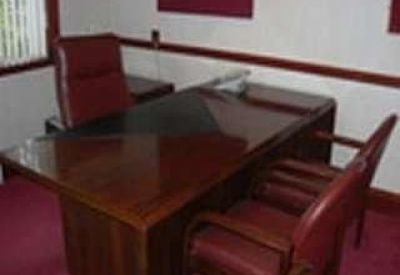 Executive office with a dark wood desk and matching leather chairs.