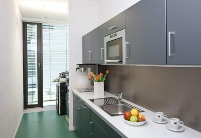 Sleek galley kitchen with dark grey cabinetry, white countertops, and integrated appliances.