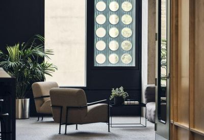 Lounge area with mid-century armchairs and a decorative circular wall feature.
