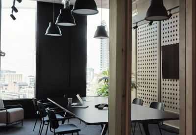 Modern meeting room with a dark conference table and industrial-style pendant lamps.