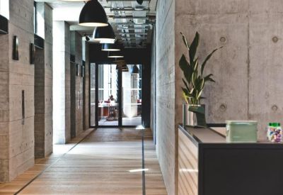 Bright concrete corridor with wood flooring and modern pendant lighting.