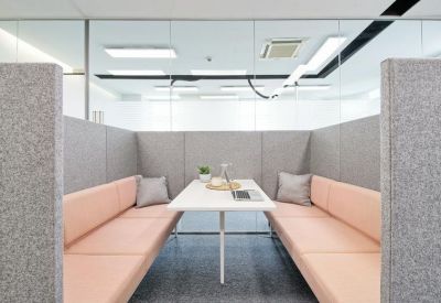 Acoustic meeting booth with pink bench seating and a central white table.