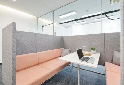 Close-up of a cozy meeting pod with grey felt walls and soft pillows.