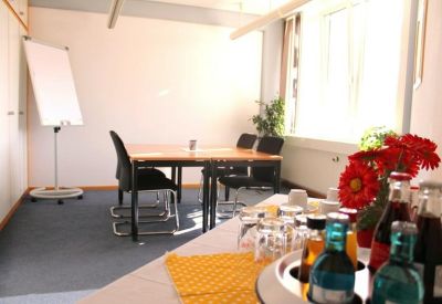 Sunlit break area with a small table, whiteboard, and a vibrant bouquet of red flowers.
