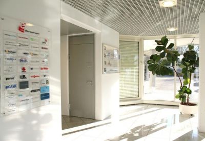 Bright white reception area with a directory sign, slatted ceiling, and large potted plant.