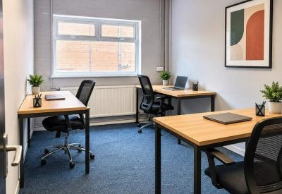 Three-person private office with wooden desks and a large window.
