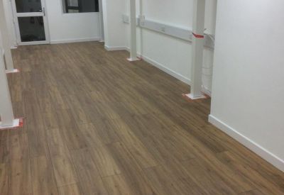 Spacious open-plan workspace featuring wood-style flooring and white structural columns.