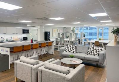 Vibrant communal lounge with grey sofas, a breakfast bar, and patterned cushions.