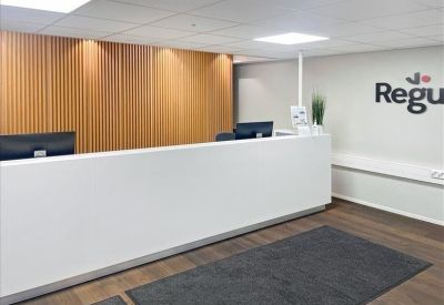 Minimalist white reception desk against a slatted wood feature wall with company branding.