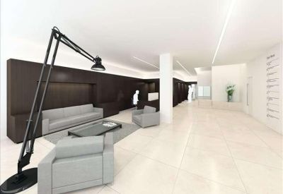 Bright white reception lounge featuring grey armchairs, a large black floor lamp, and a minimalist aesthetic.