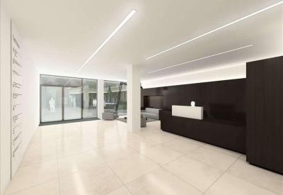 Spacious reception area with polished white floors and a long dark wood desk under linear lighting.