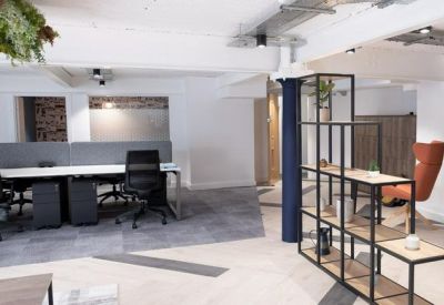 Open-plan workspace featuring long white desks, black ergonomic chairs, and a modern metal shelving unit.