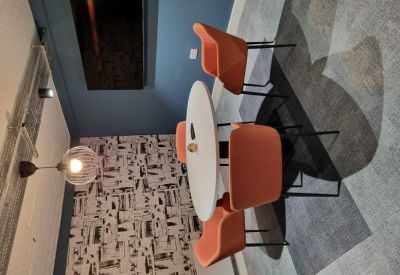 Small meeting area with a round white table, orange chairs, and a feature wallpapered wall.