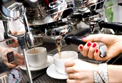 Close-up of a professional espresso machine brewing coffee into white cups.