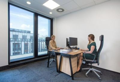 Private office with two desks and a large window overlooking the city.