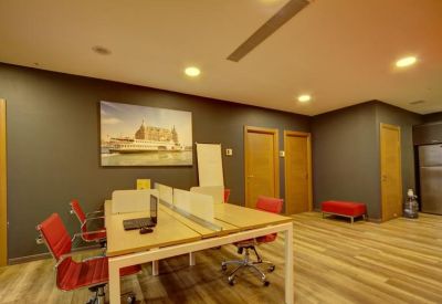 Coworking space with wooden desks, red ergonomic chairs, and a large wall mural.